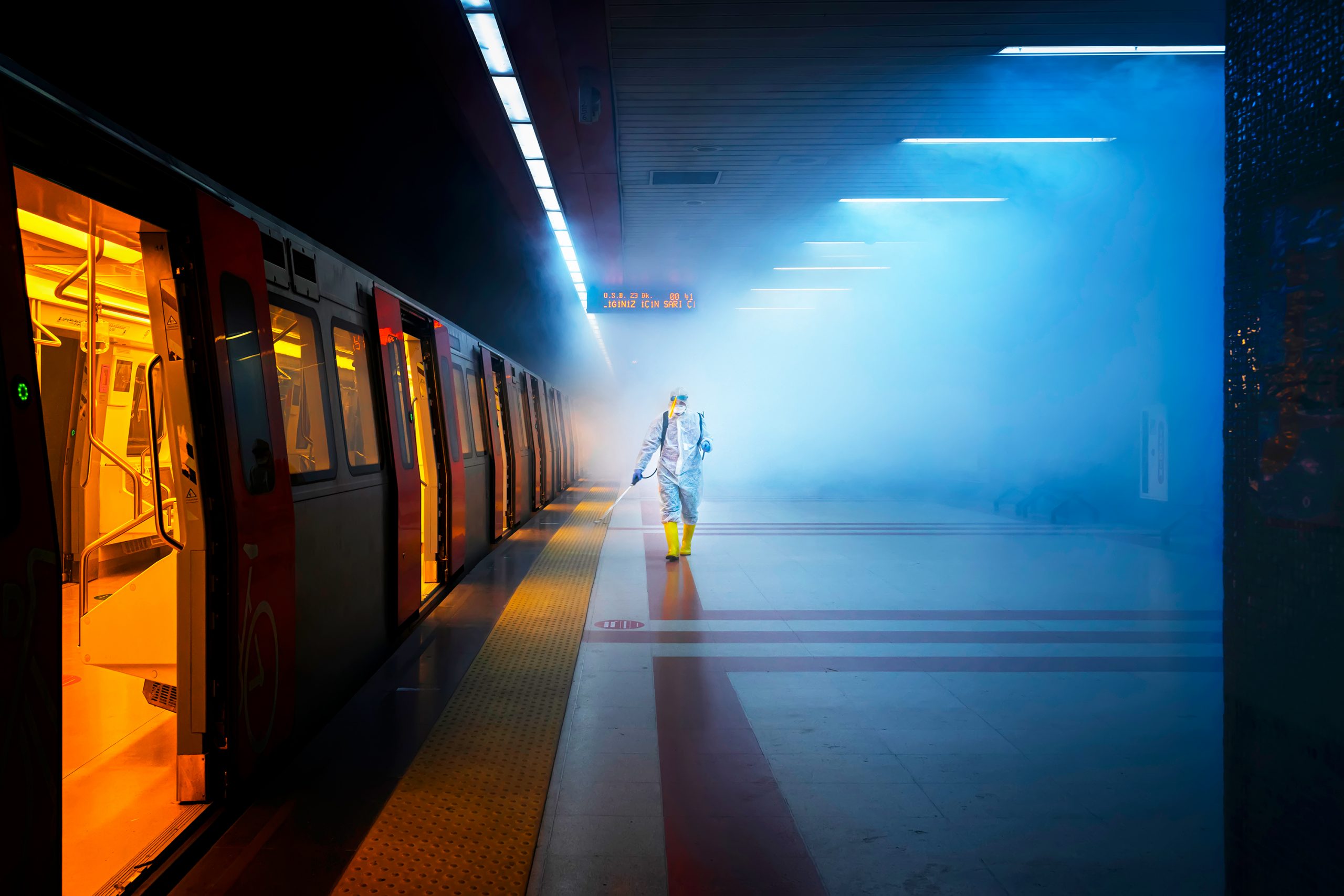 MAnn in Schutzkleidung desinfiziert Bahnsteig einer U-Bahn
