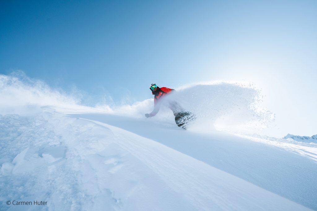 Snowboardfahrer im Tiefschnee und blauem Himmel