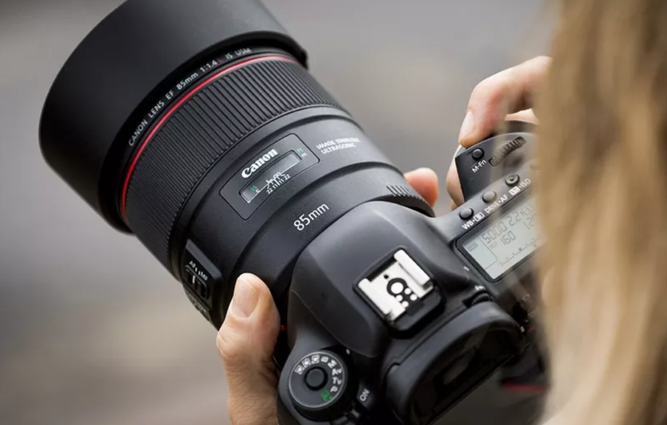 Frau hält canon DSLR-Kamera mit einem 85mm EF-Objektiv in den Händen